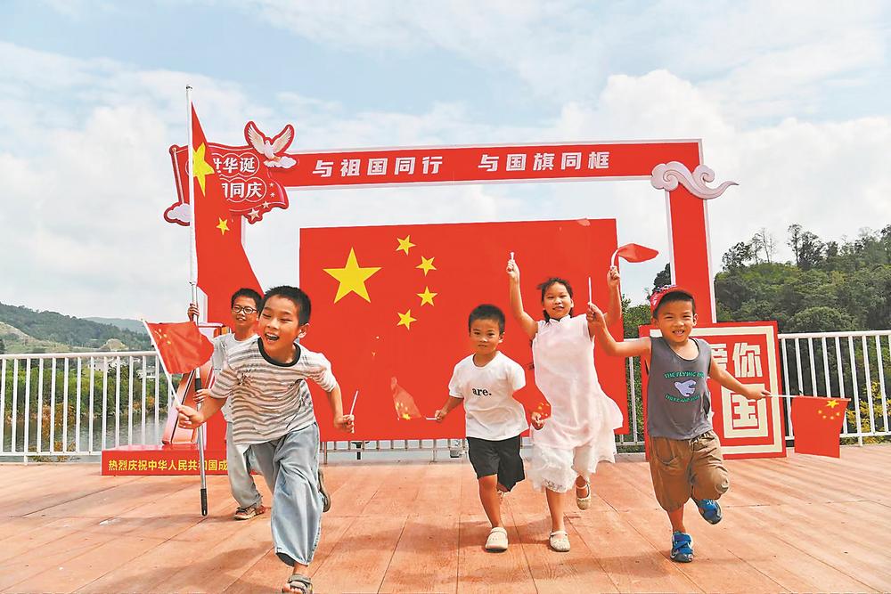 1日，在德化县龙门滩镇湖心岛，几名孩童在国庆主题装置前玩耍。 许华森 肖蔚男 摄